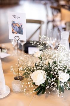 a table topped with white flowers and baby's breath next to an empty card