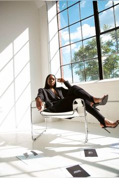 a woman sitting in a chair with her feet up on the ground and looking at the camera