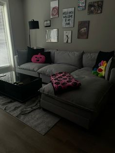 a living room with grey couches and pictures on the wall above it's coffee table