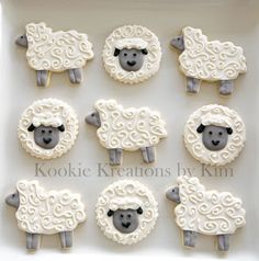 twelve sheep decorated cookies in the shape of lambs on a white platter with swirly icing