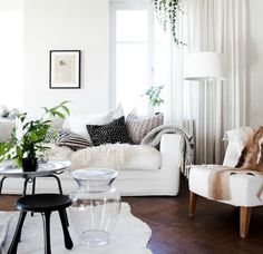 a living room filled with white furniture and lots of plants on the windowsills