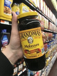 a hand holding a jar of molasses in a store