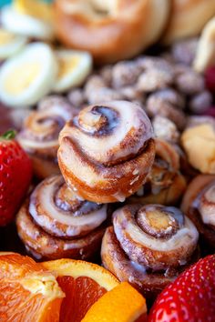 there are many different types of pastries on the table with oranges and strawberries