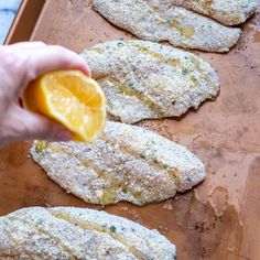 someone is holding an orange slice over some food on a wooden tray with other foods