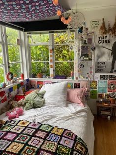 a bedroom with a bed, window and lots of posters on the wall above it