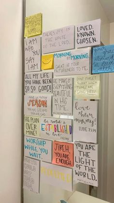 a bulletin board that has been placed on the wall in front of a mirror with post - it notes attached to it