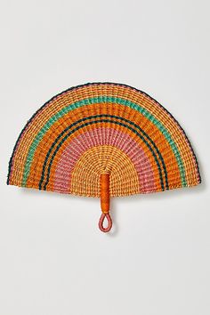 an orange and green hand fan hanging on a wall