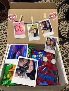 an open cardboard box with photos and pictures hanging on clothes pins