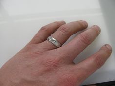 a person's hand with a wedding ring on it