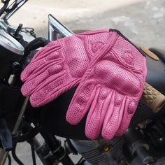 a pair of pink gloves sitting on top of a motorcycle