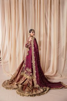 a woman in a red and gold bridal gown posing for the camera with her hands on her hips