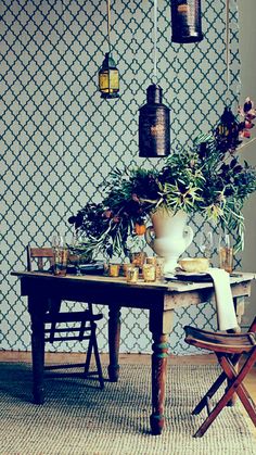 a dining room table and chairs with flowers in vases hanging from the ceiling above it