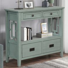 a green console table with two drawers and some books on the bottom shelf next to it