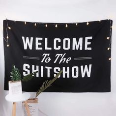 a black and white sign that says welcome to the shitshow hanging on a wall