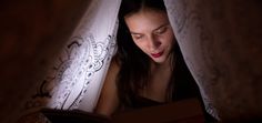 a woman is reading a book in the dark with her eyes closed and looking down