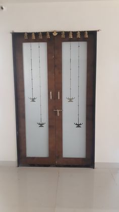 two wooden doors with white glass and gold decorations on each door, in an empty room