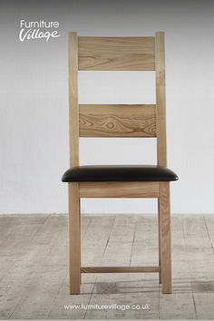 a wooden chair sitting on top of a hard wood floor next to a white wall