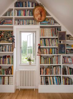 a bookshelf filled with lots of books next to an open window in a room