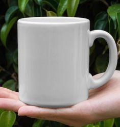 a person holding a white coffee mug in their hand