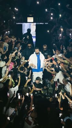 a man standing in front of a crowd of people holding cell phones and taking pictures