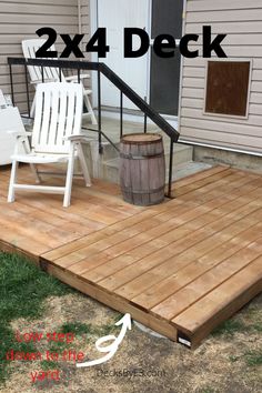 a wooden deck with two white chairs and a barrel on the ground next to it