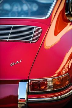 the front end of an old red car with chrome grills and emblem on it