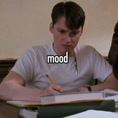 a young man sitting at a desk writing in a notebook with the words mood on it