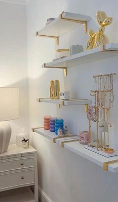 the shelves in this bedroom are decorated with gold and white accessories, such as necklaces