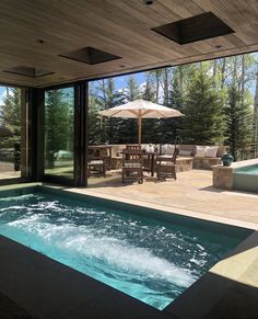 an outdoor hot tub with patio furniture and umbrellas on the deck overlooking a pool