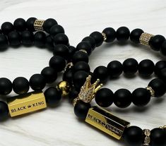 Celebrate the strength, unity, and regal essence of Black love with these exclusive Black King & Queen Matte Bead Bracelets. Perfect for couples who want to showcase their royal connection, these matching bracelets are more than just accessories--they're a statement of power and partnership. -Made with 10 mm black matte beads that provide a sleek, modern look, complemented by gold accents and crowns that symbolize royalty. -Each bracelet features a bold, gold-tone bar engraved with "BLACK KING" and "BLACK QUEEN," highlighting the pride and honor in your bond. - Anniversary gifts - Valentine's Day - Birthday presents - Couples who want to wear matching jewelry that symbolizes their love and connection - The bracelets are made to order according to size chart. They are crafted on a strong, s King Crown Bracelet, Couples Matching Bracelets, His And Hers Bracelets, Black King And Queen, Bracelets Black, Black King, Love Jewelry, Valentines Day Birthday, Matching Jewelry