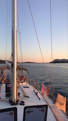 the front end of a sailboat with people on it in the water at sunset