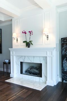 a living room with a white fireplace and wooden floors