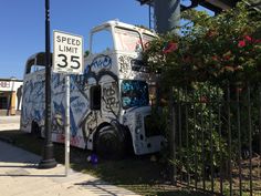 an old truck with graffiti on it parked in front of a street sign and fence