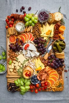 an assortment of cheeses, fruits and crackers on a platter