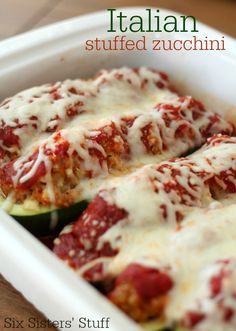 stuffed zucchini in a white casserole dish with sauce and cheese on top