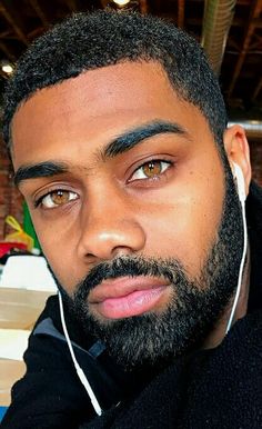 a man with headphones on his ears is looking at the camera while sitting in an office