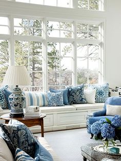 a living room filled with blue and white furniture in front of a large open window