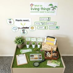 a table with plants, seed packets and other items on it in front of a living things sign