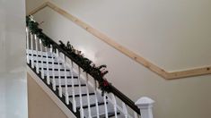 the stairs are decorated with christmas garlands and greenery on each handrail, along with white balconies