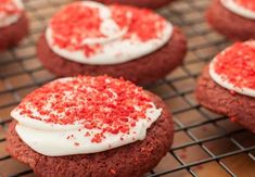 red velvet cookies with white frosting and sprinkles on a cooling rack