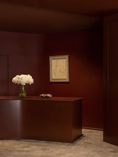 a vase filled with white flowers sitting on top of a wooden desk next to a doorway