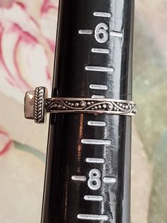 This is a vintage ring with square, faceted, peridot stone and designs on the band. The ring is stamped and has tested positive for sterling silver. There is something on the interior of the band that I can't make out. Sarah, possibly? This is a size 7 and cannot be sized due to the design on the band. Don't forget to stop in at my other Etsy shop... http://www.etsy.com/shop/xtdesigns. Follow me on Twitter at... MyYiayiaHadThat@MyYiayiaHadThat. If you have a wish list or are looking for somethin Adjustable Rectangular Engraved Ring For Anniversary, Vintage Adjustable Rectangular Ring, Adjustable Rectangular Sterling Silver Ring, Rectangular Promise Ring Stamped 925, Vintage Silver Ring With Rectangular Stone, Vintage Silver Rings With Rectangular Stone, Adjustable Sterling Silver Ring With Rectangular Stone, Vintage Adjustable Gemstone Stackable Rings, Win My Heart