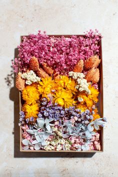 an arrangement of flowers in a wooden box on the ground with no people around it