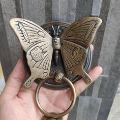 a person holding a butterfly shaped keychain in their hand