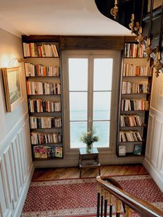 a room filled with lots of books on top of a book shelf next to a window