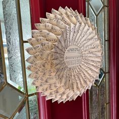 a wreath made out of sheet music sits in front of a red door