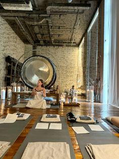 a woman is sitting on the floor in front of some yoga mats