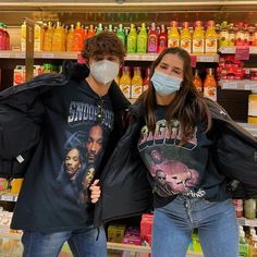 two people wearing face masks standing in front of a store shelf with orange juices