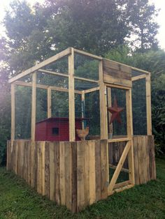 a small wooden structure with a chicken in it's cage on top of grass