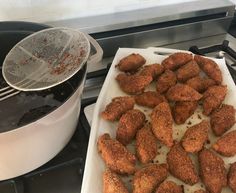 chicken nuggets are being cooked on the stove with a strainer over them